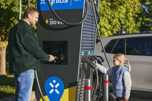 Isa õpetab tütart, kuidas laadida Ignitis ON elektriauto laadimisjaamas.